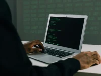 A focused adult working on a laptop demonstrates modern cybersecurity and coding skills indoors.